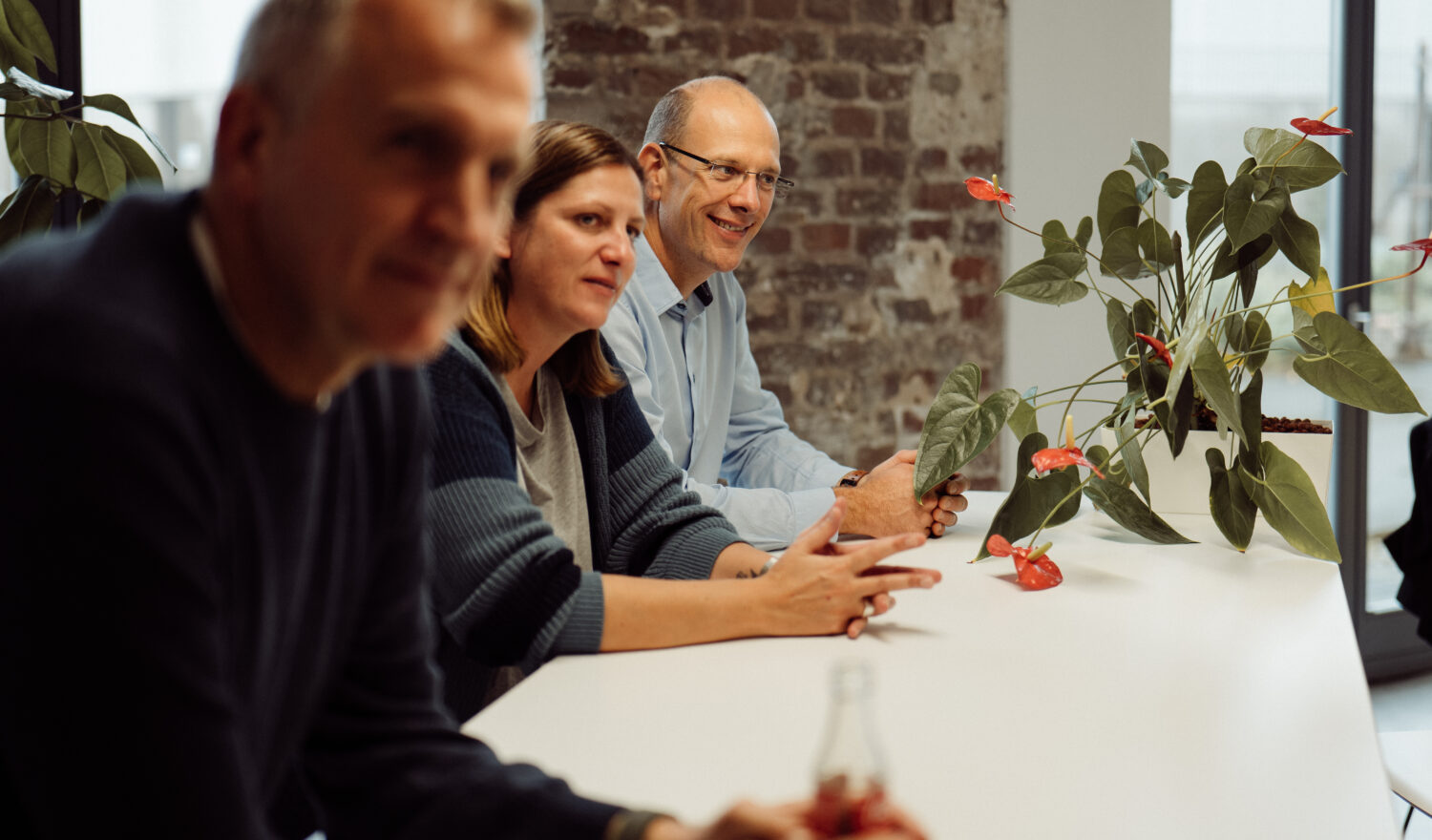 Drei Personen sitzen am Tisch und hören aufmerksam zu