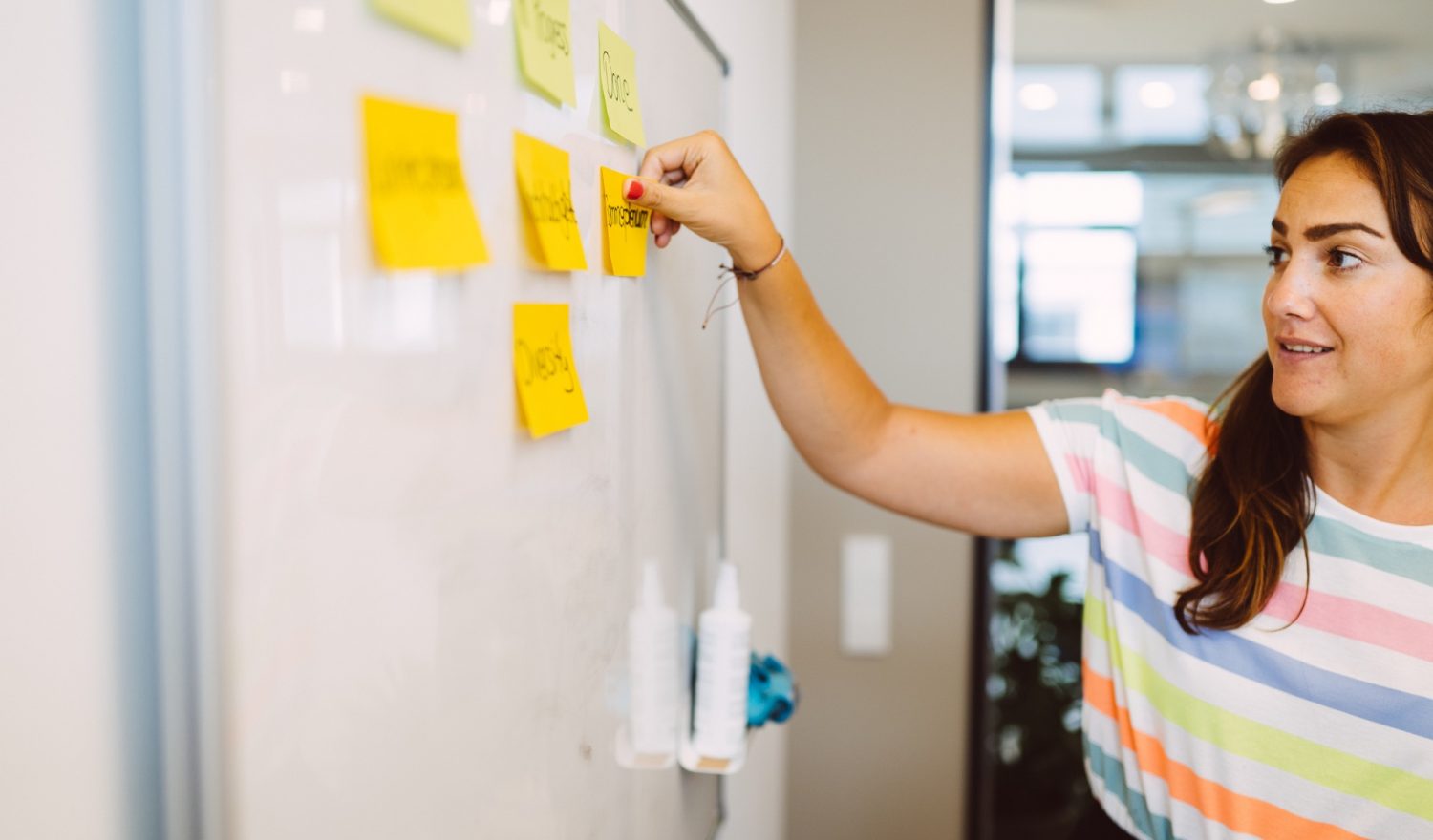 Eine Frau klebt Notizzettel an ein Whiteboard