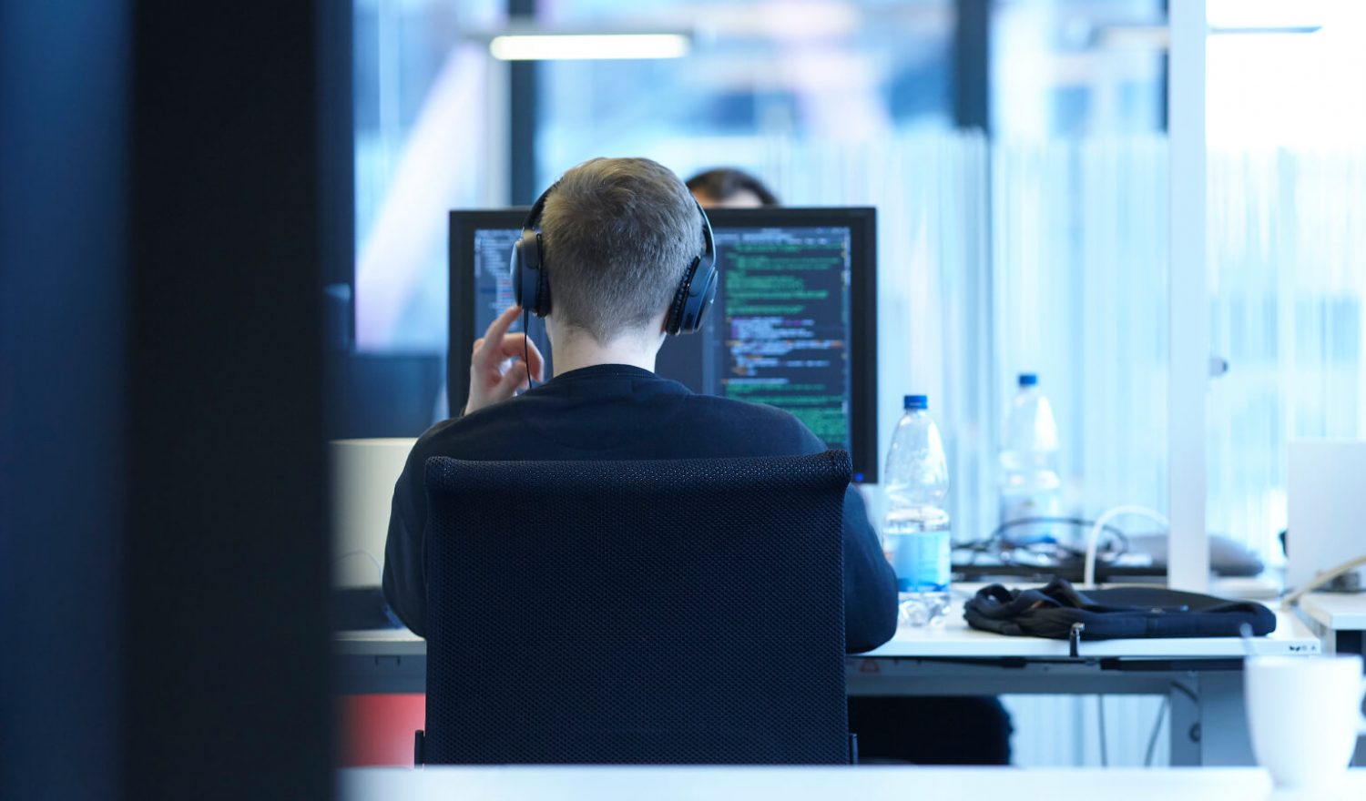 Rückenansicht eines inovex-Mitarbeiters im Arbeitsbereich