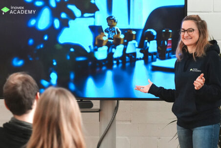 Eine Person steht neben einem Bildschirm und hält eine Präsentation