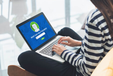 Frau sitzt mit Laptop Chatbot