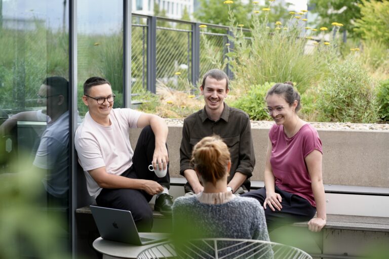 Vier Personen, die auf einer Terrasse sitzen und sich unterhalten.