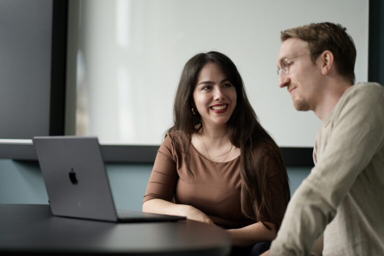 Zwei Personen sitzen vor einem Laptop.