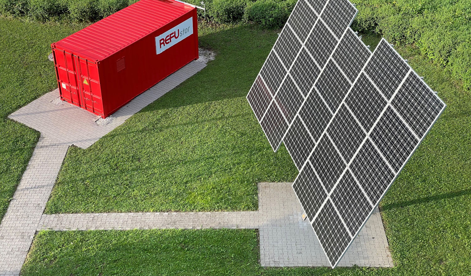EV-Boost Box in rotem Container mit Solarzellen auf Rasen