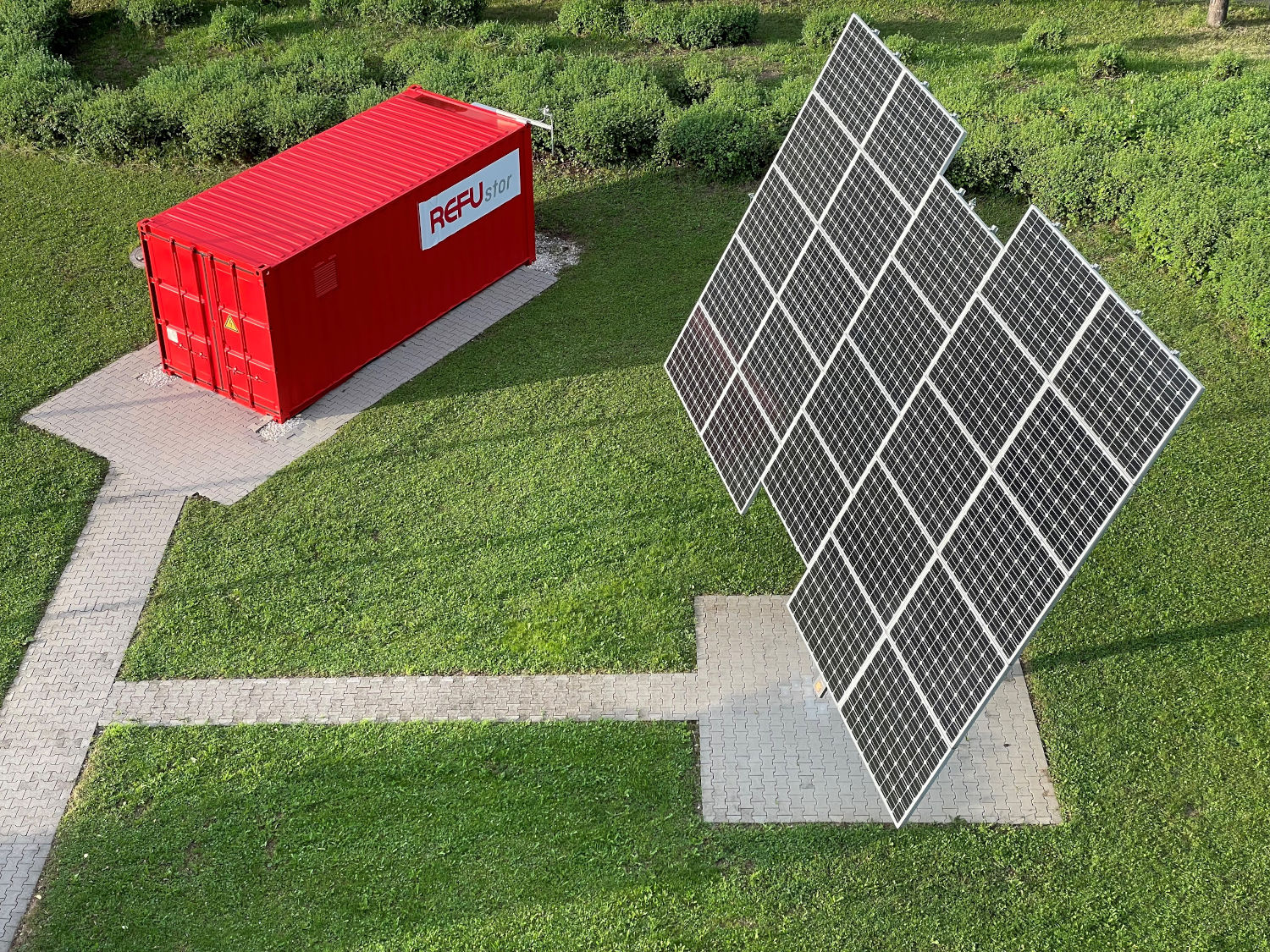 EV-Boost Box in rotem Container mit Solarzellen auf Rasen