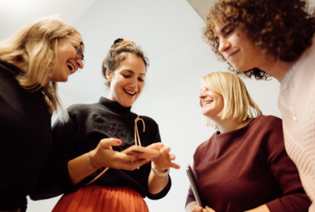 Vier inovex-Mitarbeiterinnen schauen lächelnd auf ein Handy
