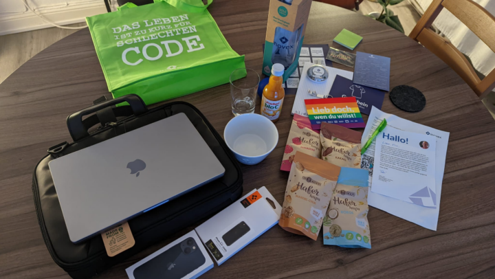 Welcome Box mit MacBook Pro, iPhone, weißer Schüssel mit inovex-Logo, Soul Bottle mit inovex-Logo, grüner Stofftasche mit Spruch, Kulli, Snacks und Brief