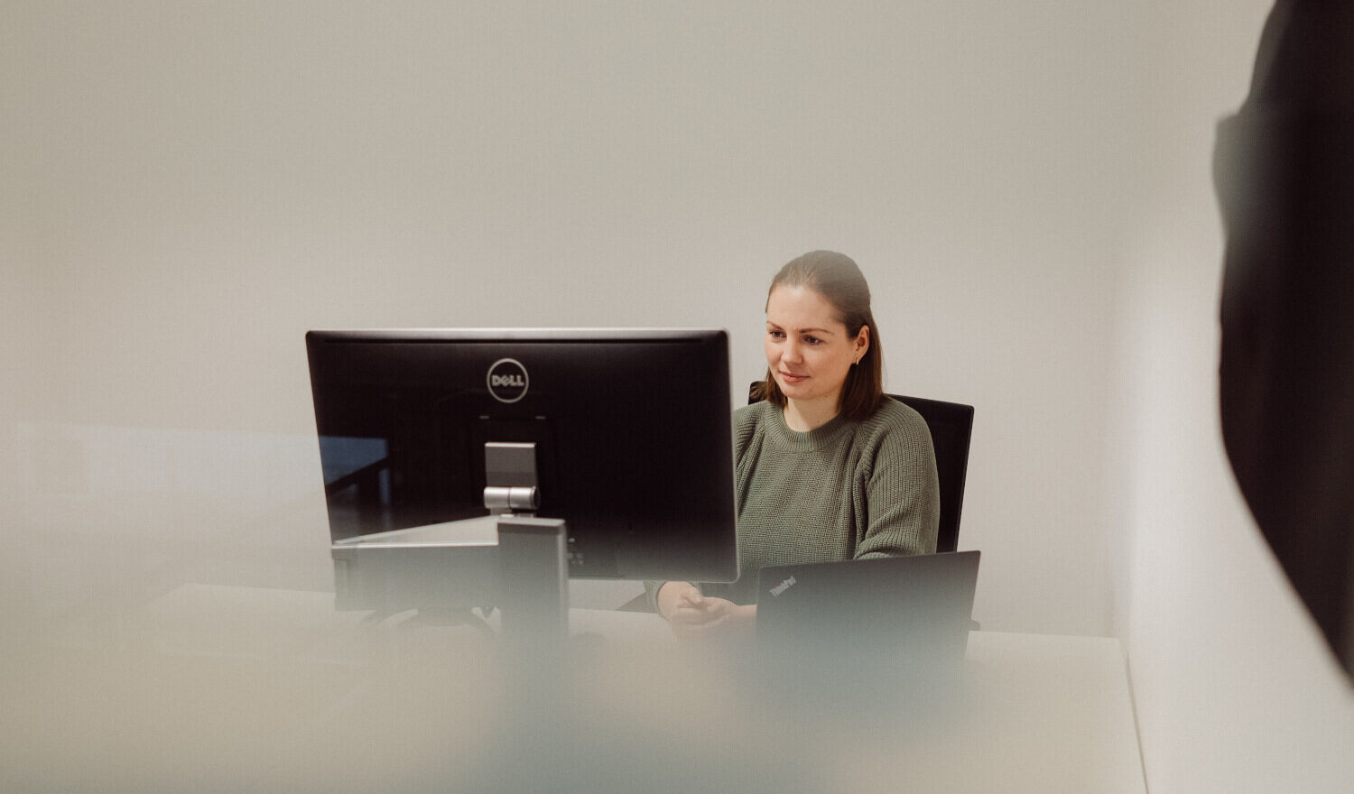 Eine Person sitzt vor einem Laptop und einem zweiten Bildschirm