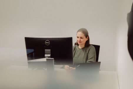 Eine Person sitzt vor einem Laptop und einem zweiten Bildschirm