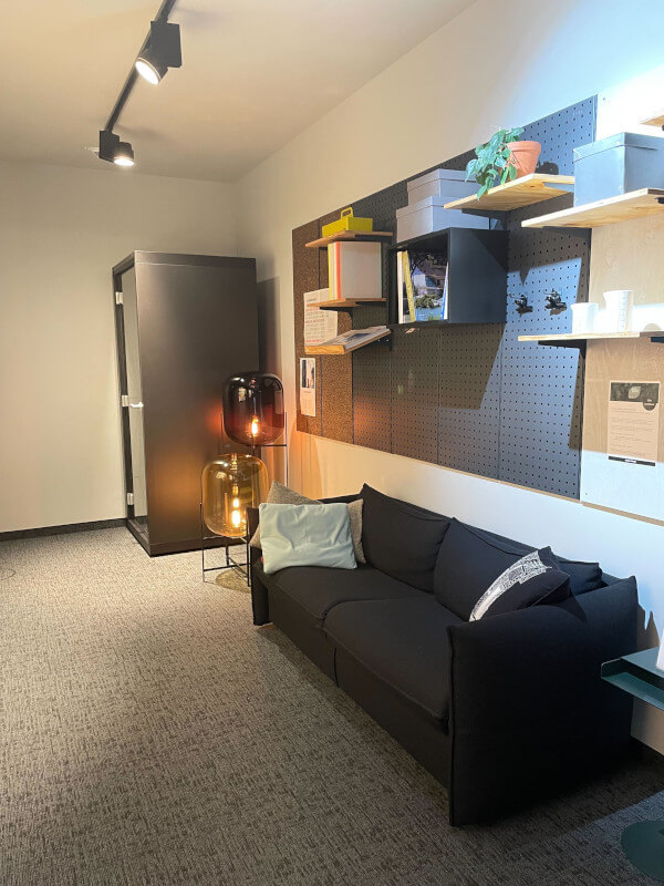 Aufenthaltsbereich mit schwarzem Sofa, Meetingbox und Regalbrettern der inovex Design Offices Berlin