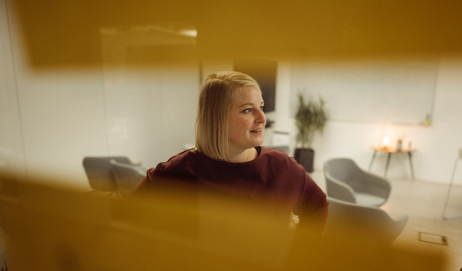 Blick durch an eine Glaswand geklebte Post-Its auf eine lächelnde Person