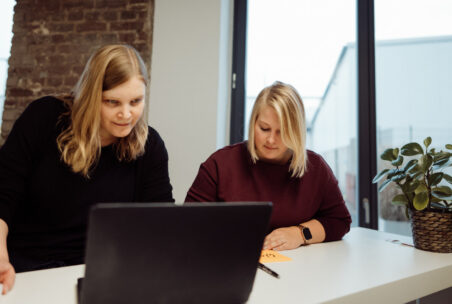 Zwei Menschen arbeiten am Laptop und schreiben Post-Its