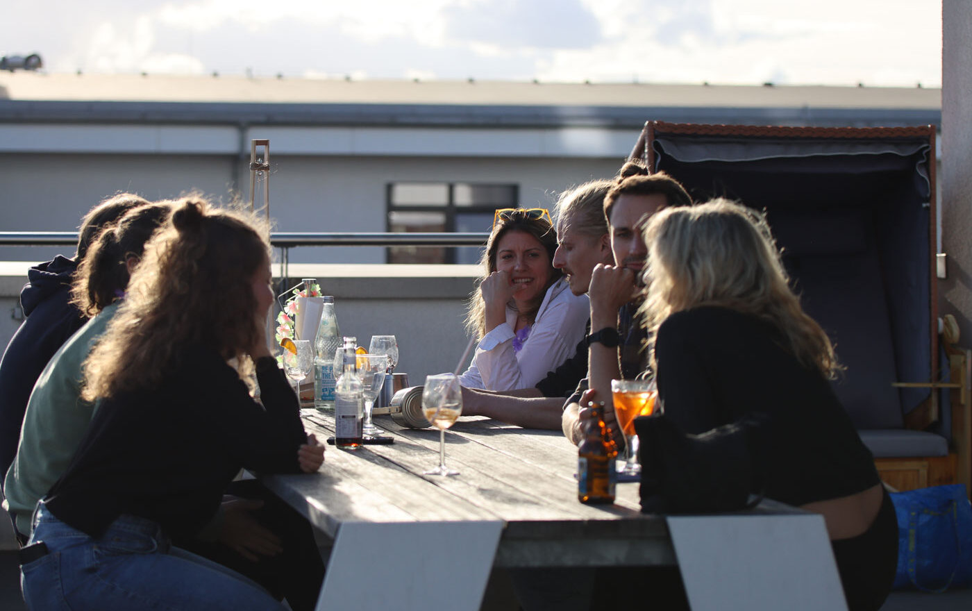 Mehrere Personen sitzen auf einer Terrasse zusammen.